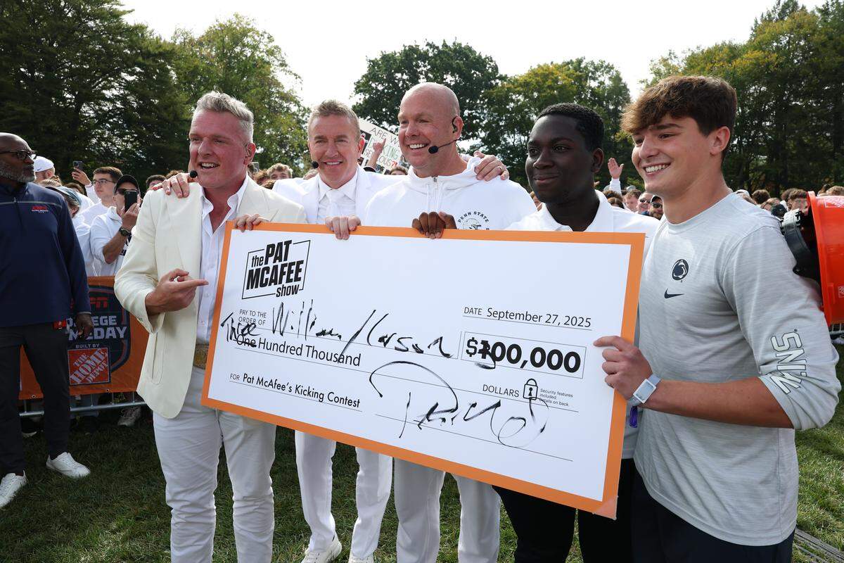 From left to right, College GameDay analysts Pat McAfee, Kirk Herbstreit and Steve Coughlin “Stanford Steve” hand an oversized check to William and Carson Albright during Saturday morning’s Field Goal Kicking Challenge segment on the set of College GameDay at Penn State. Albright kicked a 33-yard field goal to win.