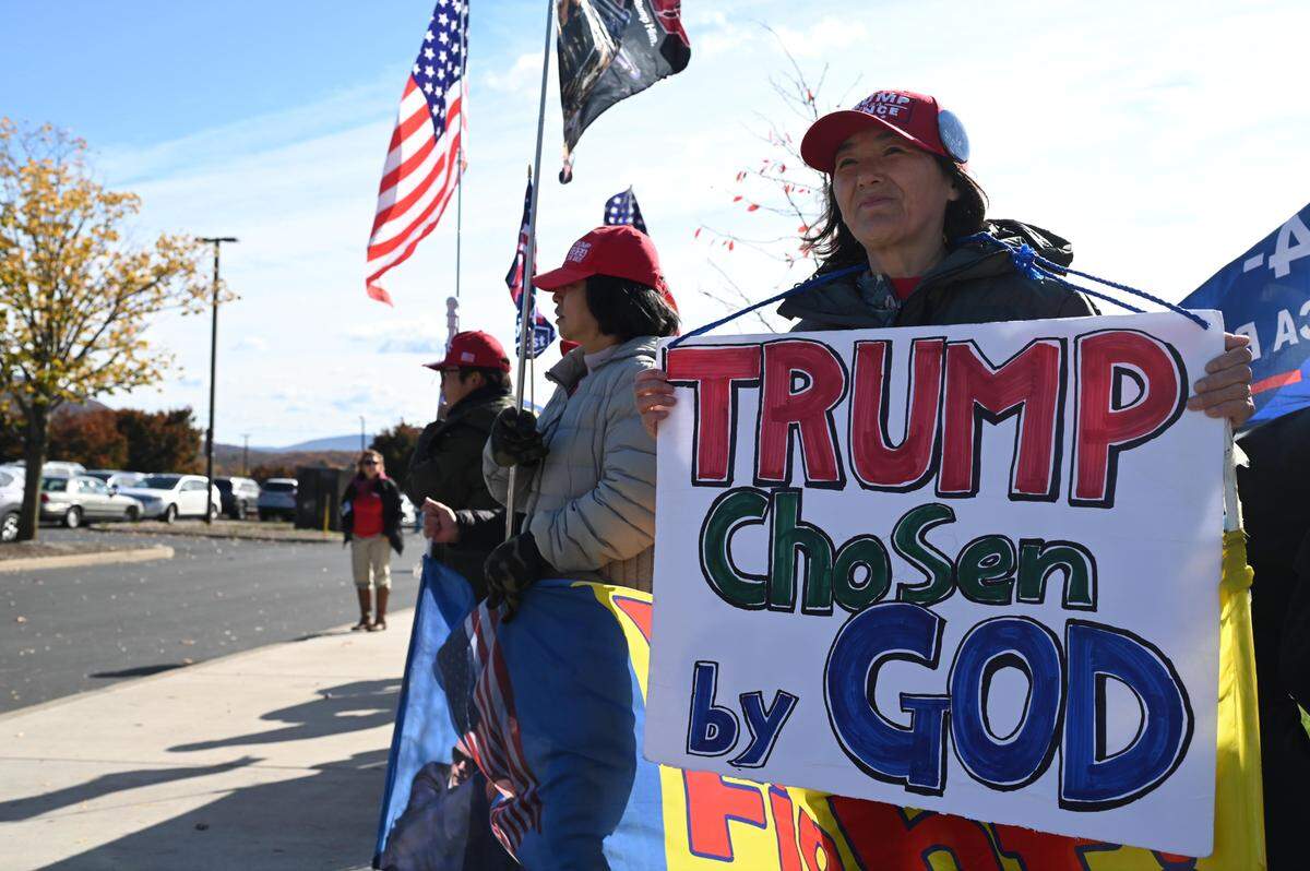 Supporters from the Rod of Iron Ministry hold signs outside the Bryce Jordan Center during a Trump rally on Saturday, Oct. 26, 2024.