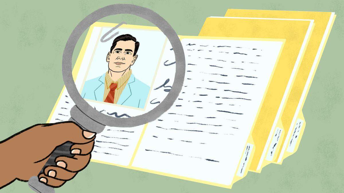 A person holds a magnifying glass up to a picture of a doctor, as part of that doctor’s file.