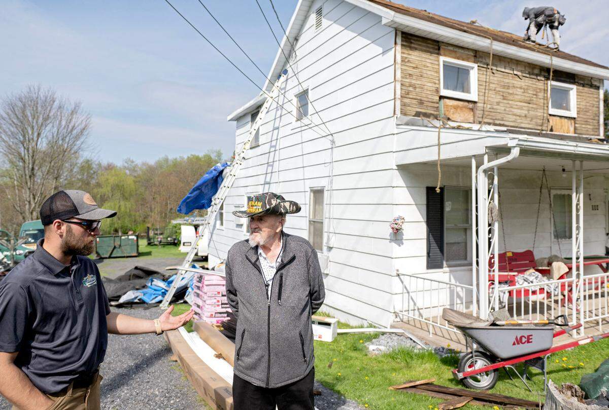 President of Starway Roof Systems Elmer Glick talks with Vietnam War veteran Gilbert Biggans as his team works to put a new roof on Biggans’ Clarence home on Thursday, May 1, 2025. Through Owens Corning Roof Deployment Project the roof and some siding of Biggans’ home were replaced.