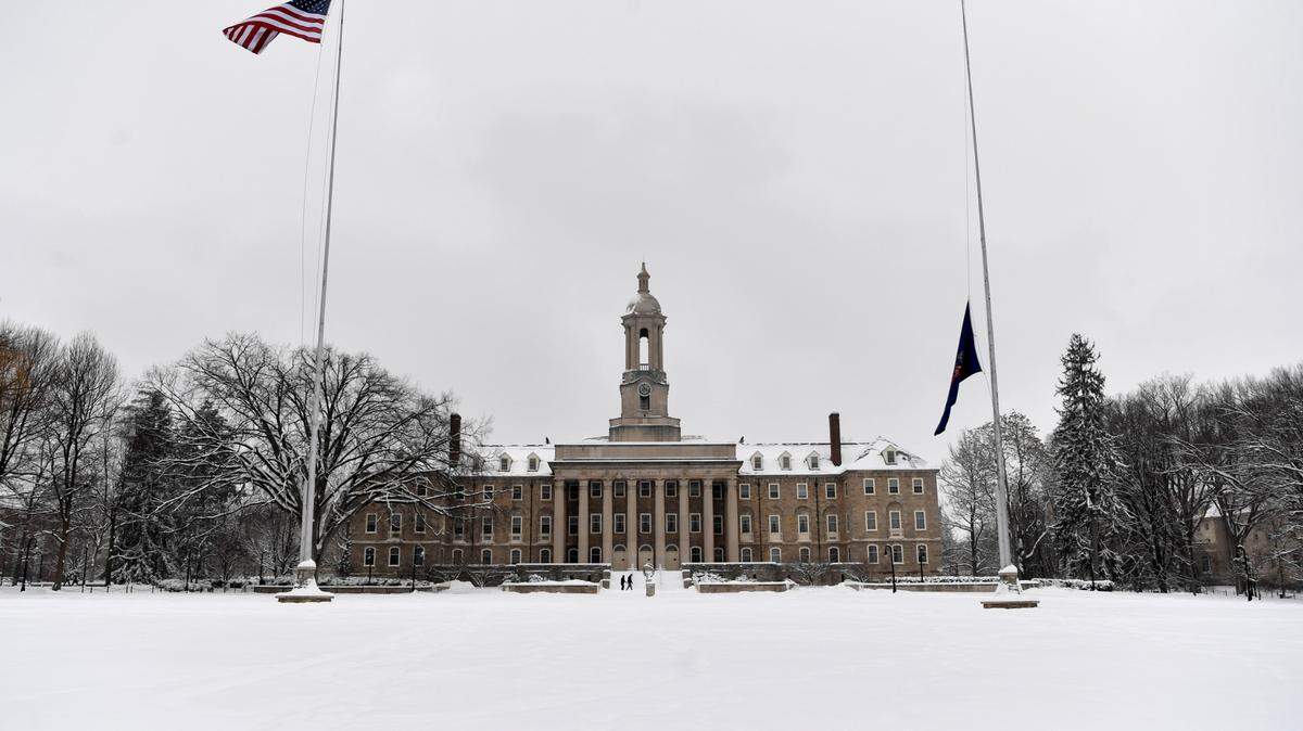 People walk in front of Old Main on the Penn State campus in the snow on Monday, Feb. 1, 2021.