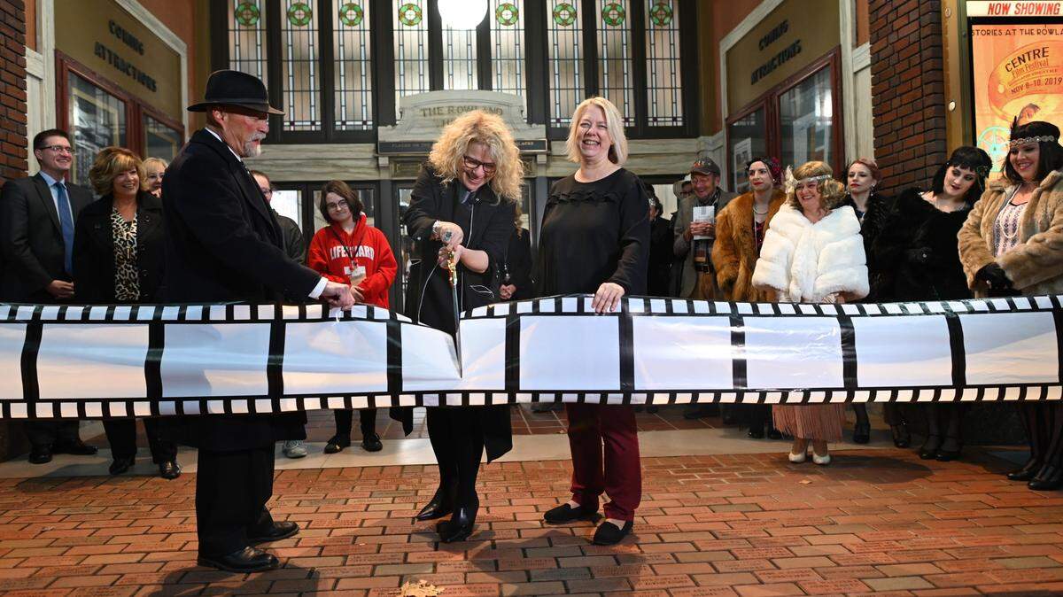 Filmmaker Pearl Gluck cuts a ribbon of film to officially open the inaugural Centre Film Festival at the Rowland Theatre in Philipsburg on Nov. 8, 2019.