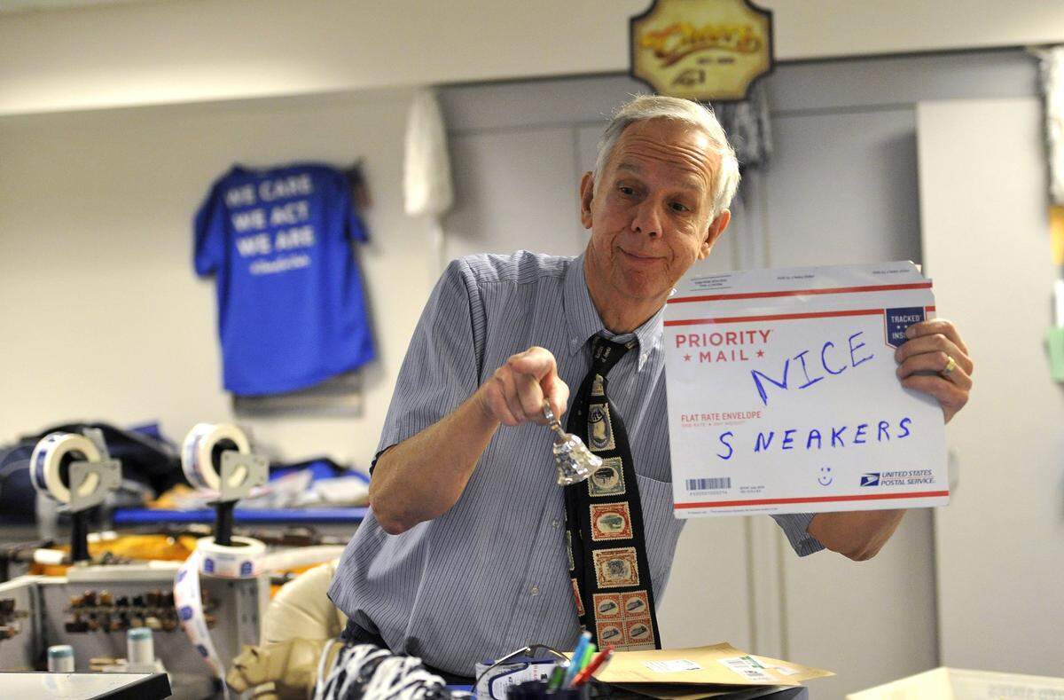 Mike Herr holds up a sign and rings a bell as a girl with colorful shoes walks into the post office in February 2016. Herr, otherwise known as "Mike the Mailman," served customers in the post office located on the Penn State University campus for 48 years. 