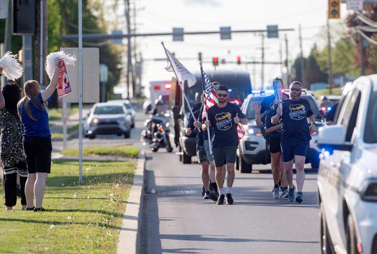 Members of the Ferguson Township police department run the final leg of the Law Enforcement Torch Run for the Special Olympics on Thursday, May 12, 2022. Carrying the American Flag is Bryan Greene and Derek Hoover carries the torch as they run along North Atherton Street.