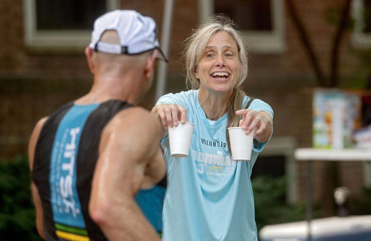 Volunteer Meira Minard holds out water for athletes during the Ironman 70.3 Pennsylvania Happy Valley on Sunday, June 30, 2024.