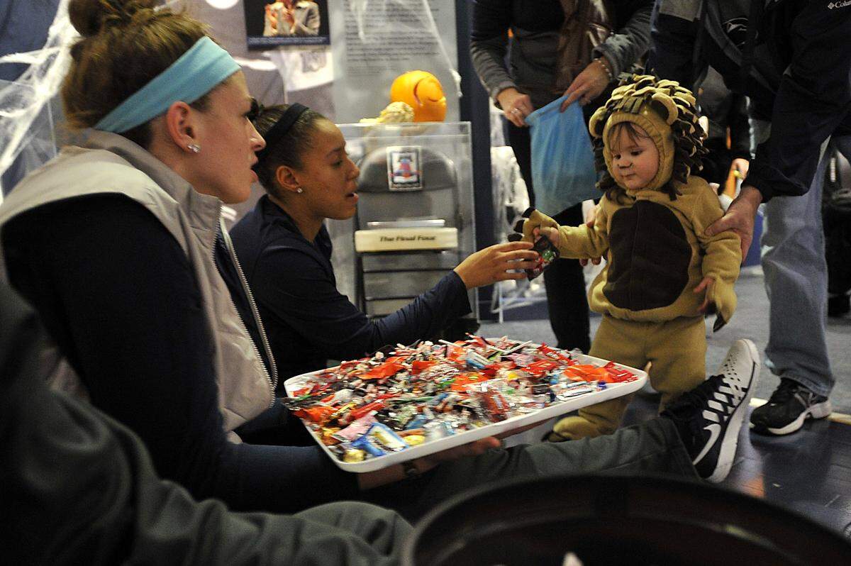 Giovanni Italia, 1, takes a piece of candy from Lady Lion basketball players at the Penn State All-Sport Museum Trick or Treat event in 2013.