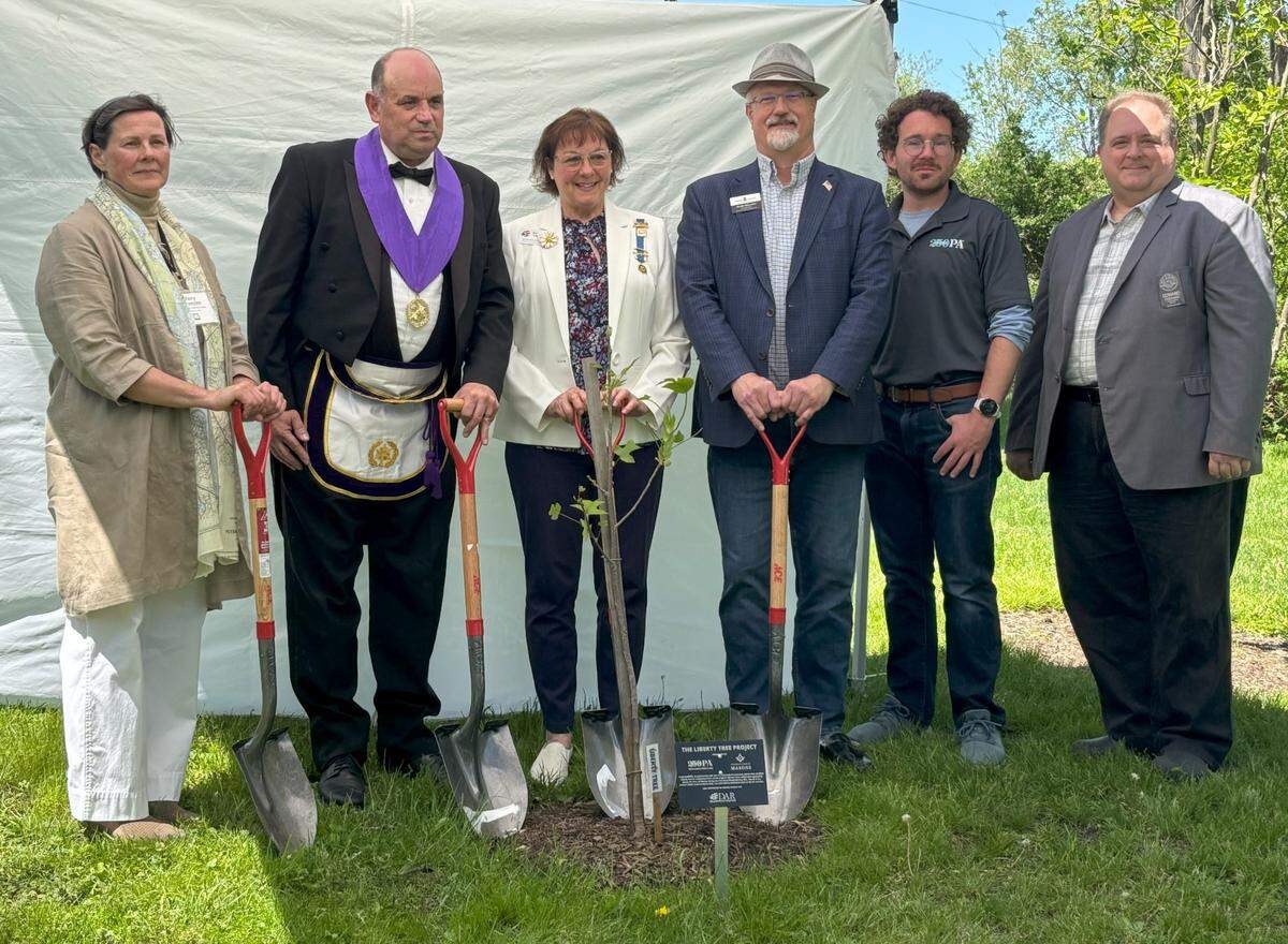A sapling taken from the clone of a historic Liberty Tree, where American revolutionaries once met, was planted Saturday afternoon on the grounds of Centre Furnace Mansion in State College ahead of America’s 250th birthday next year. Among those posing, from left to right, include Mary Sorensen, executive director of the Centre County Historical Society; John Segursky, district deputy grand master of the 21st Masonic District; Barbara Hughes, regent for the Bellefonte chapter of the Daughters of the American Revolution; Centre County Commissioner Mark Higgins; Christian Cassidy-Amstutz, America250PA’s Strategic Initiatives & Grants Manager; and Edward Stoddard, communications director for the Happy Valley Adventure Bureau.