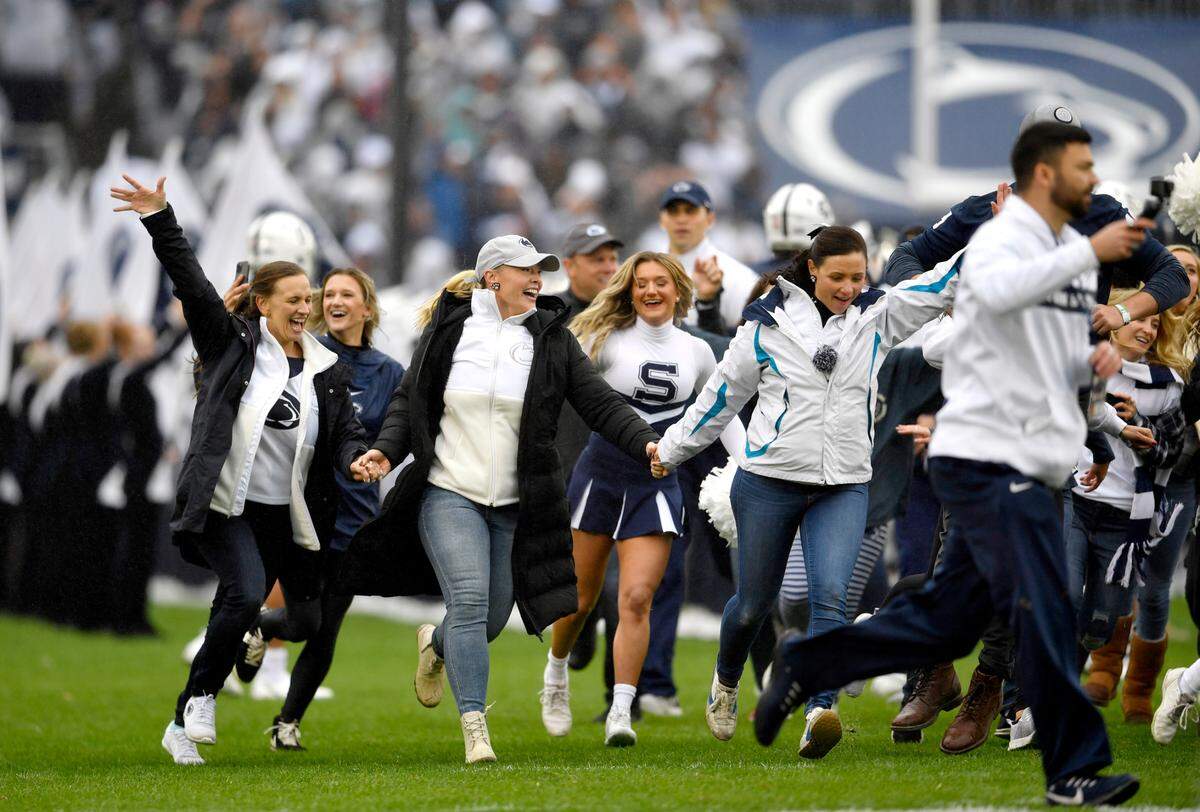 Penn State alumni cheerleaders run across the field to welcome the Penn State player to the field for the game against Illinois on Saturday, Oct. 23, 2021 as part of the homecoming celebrations.