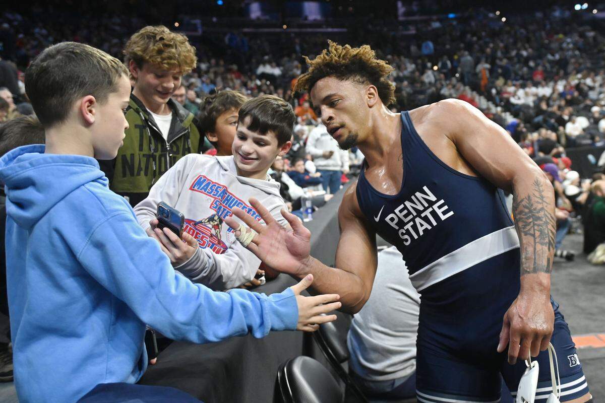 Penn State’s Greg Kerkvliet stops to take photos and high-five young fans after he won his 285-pound quarterfinal bout at the 2025 NCAA Wrestling Championships in Philadelphia on Friday, March 21, 2025.