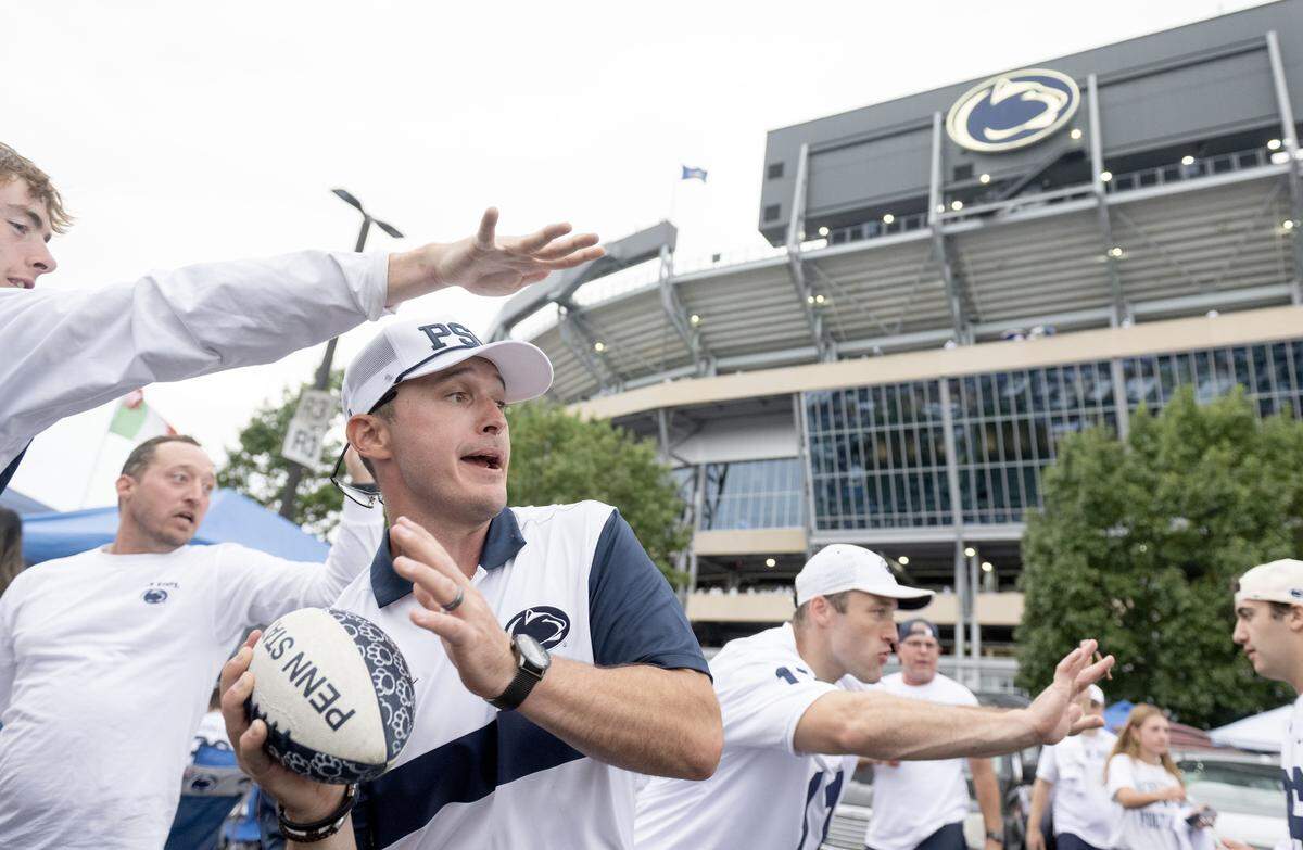 Andrew Starr makes a pass to fans walking by his tailgate outside of Beaver Stadium before the Penn State game against Oregon on Saturday, Sept. 27, 2025.  