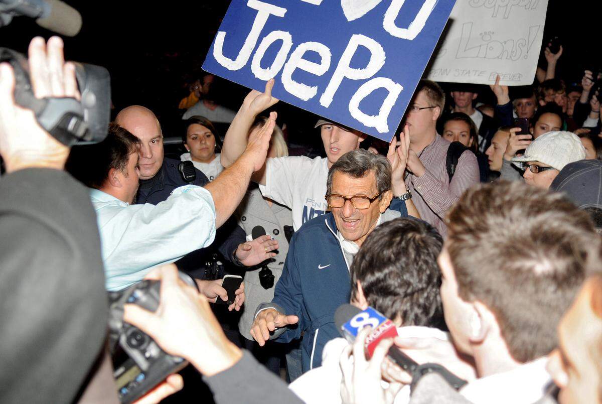 Penn State football coach Joe Paterno walks down his driveway through a crowd of students who gathered in his support after a football practice on Nov. 8, 2011.