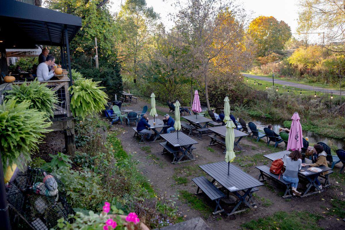Customers have drinks and food by the creek at Voodoo Brewery in State College on Tuesday, October. 24, 2023.