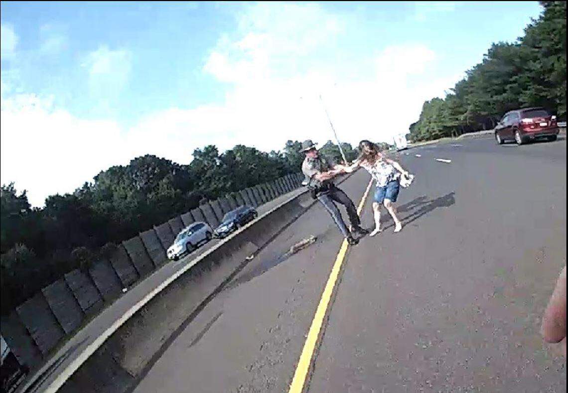 In the photos, a trooper is seen engaged in a tug of war with the woman, pulling her by one arm out of travel lanes as she struggles to break run into oncoming traffic.