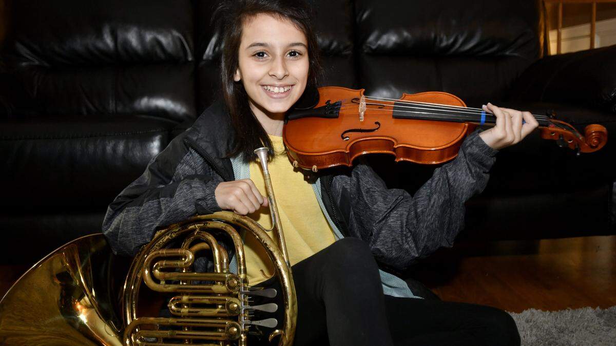 Ashley Gardner poses with her French horn and violin on Wednesday. A sixth-grader at Mount Nittany Middle School, Ashley composed a piece of music for the Nov. 14  Partners in Music Elementary Band and Orchestra Concert.