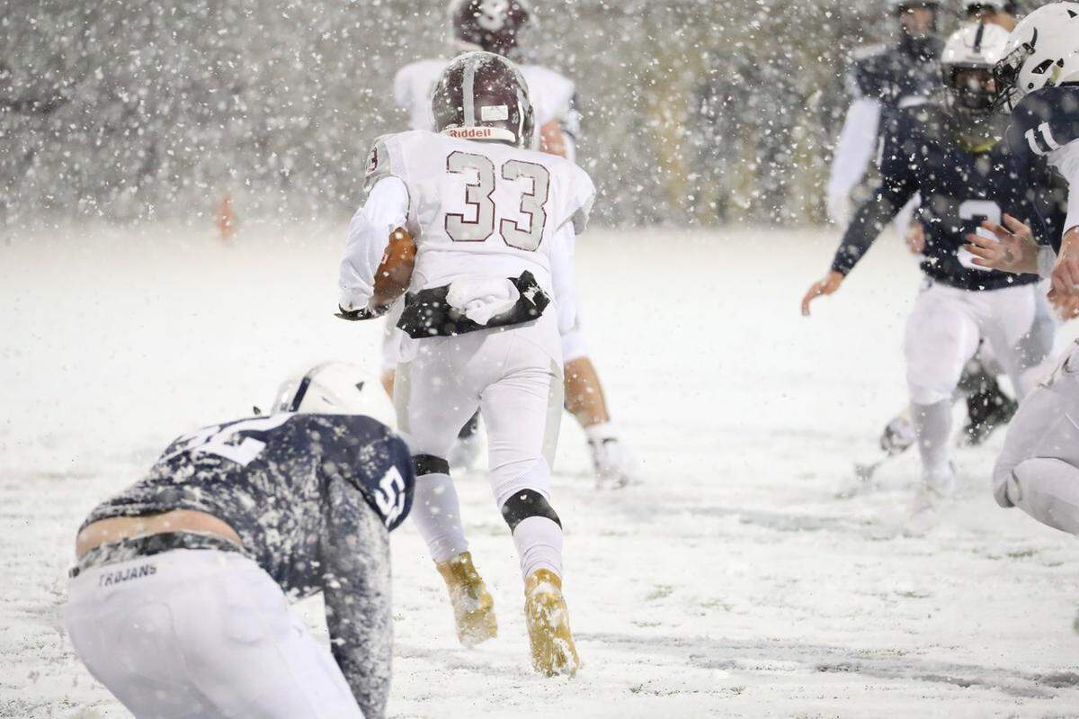 State College’s Nehemiah Howell runs against McDowell defenders in the snow Friday in the PIAA Class 6A subregional football game at Erie Veterans Memorial Stadium. State College won 42-21.