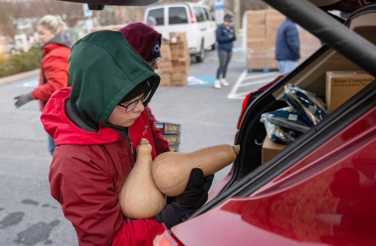 Ben Seaton, 11, and fellow volunteers help to load food into cars during the YMCA Anti Hunger program’s distribution at the Grace Lutheran Church in State College on Thursday, Nov. 17, 2022.