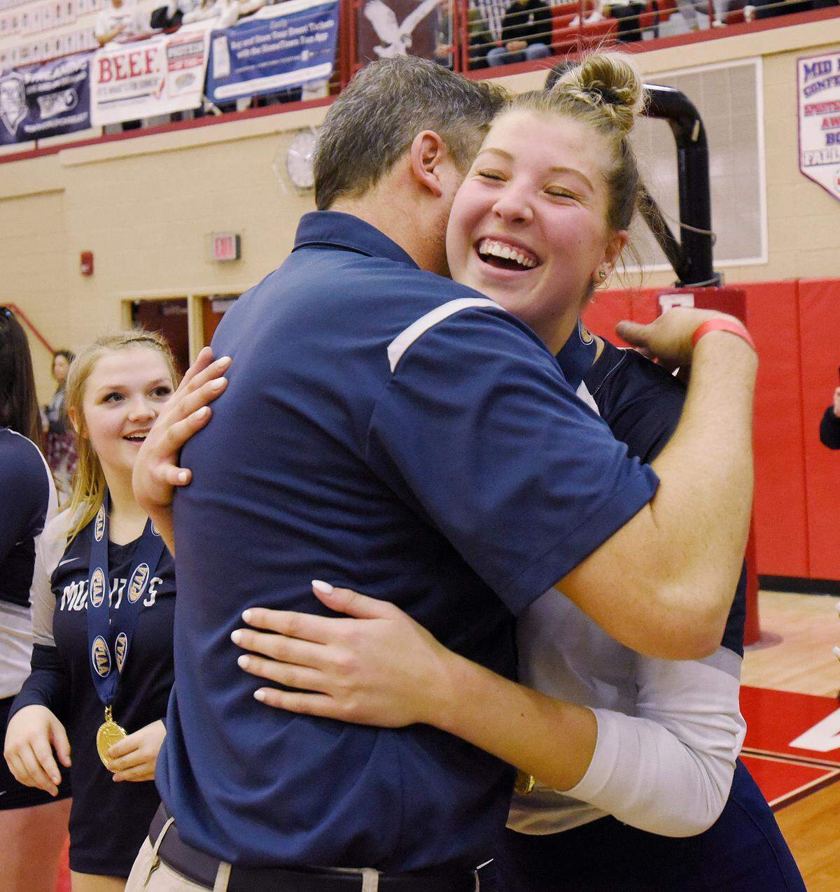 Philipsburg-Osceola’s Reese Hazelton hugs girls volleyball coach Dave Eckberg after receiving her gold medal Saturday after the Lady Mounties beat Trinity to claim the PIAA Class 2A state championship in Mechanicsburg at Cumberland Valley. P-O won 3-1.