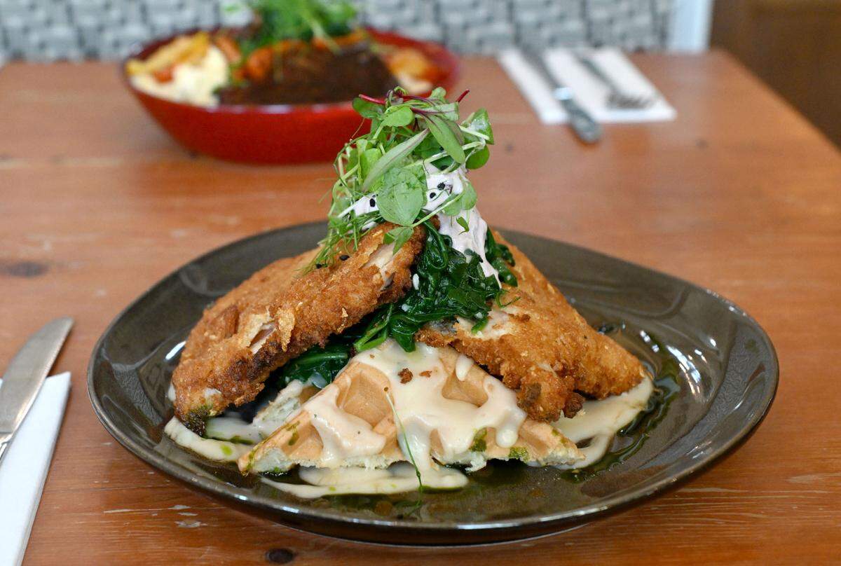 The southern deconstructed chicken & waffle at Gigi’s Southern Table. The sweet and savory dish has frosted flake-crusted chicken, sage velouté gravy, 100% maple syrup, lingonberry crème fraîche and garlic-braised spinach.