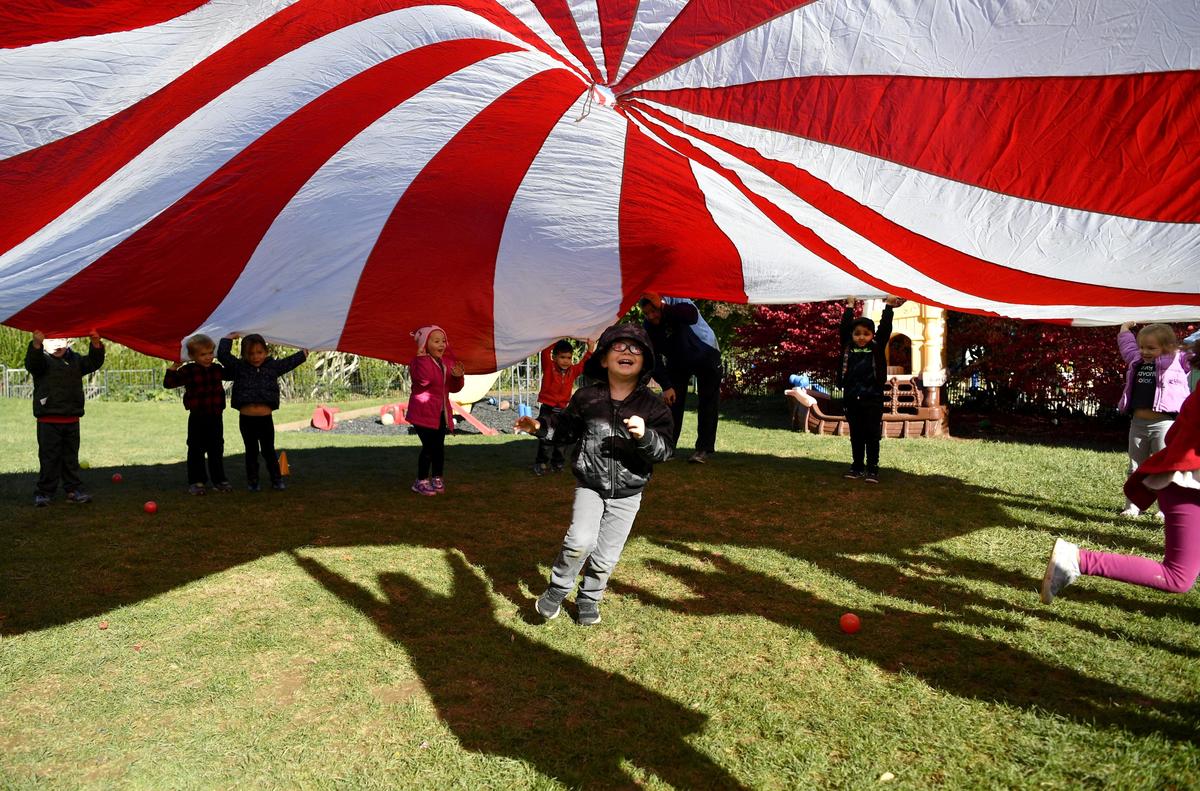 Mason, 4, runs under the parachute as he and his classmates in the Pre-K Counts class do an activity on Thursday at the Learning Station.