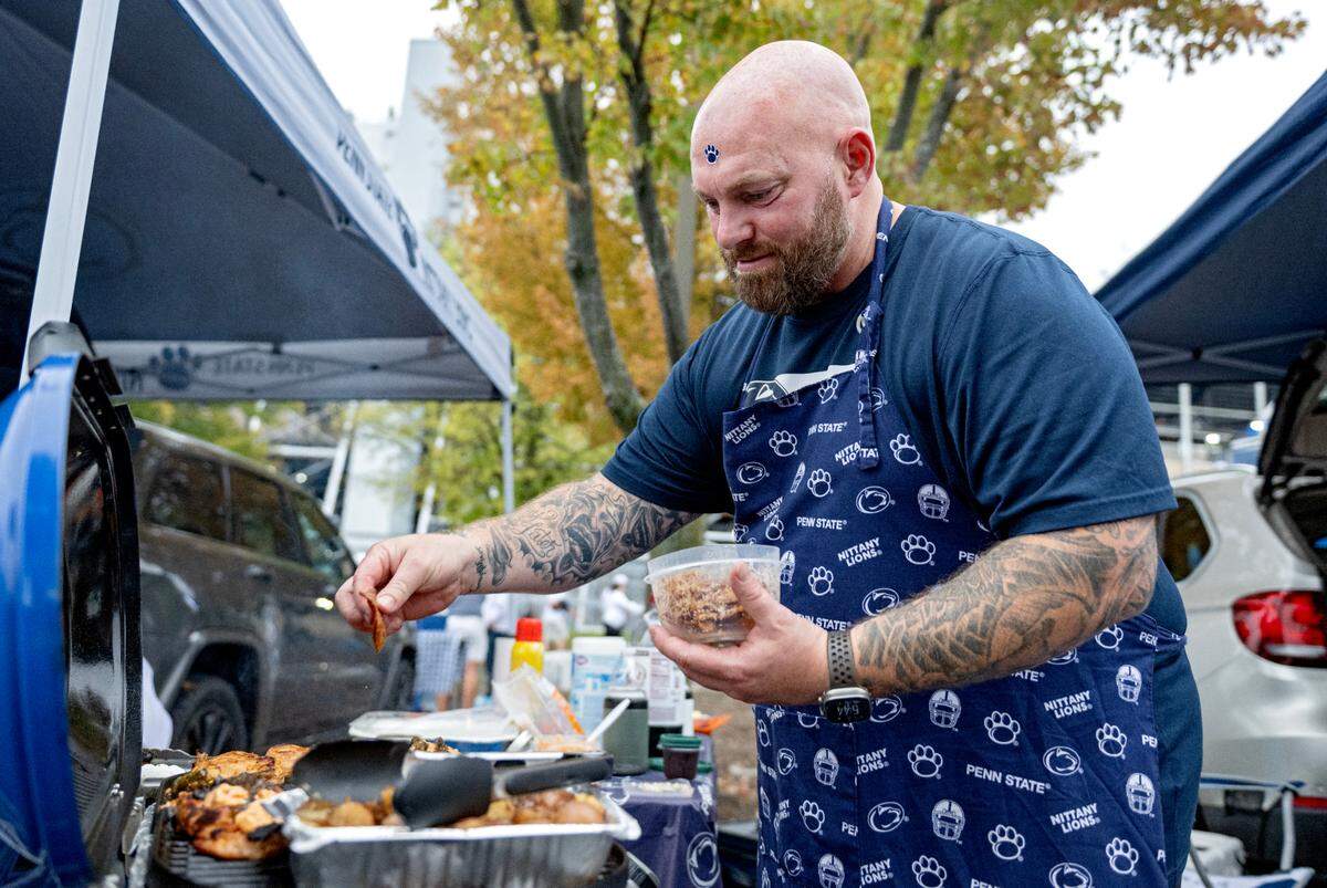 Penn State fan Drew Kendall grills chicken with bacon and cheese outside of Beaver Stadium before the Homecoming game on Saturday, Sept. 28, 2024.