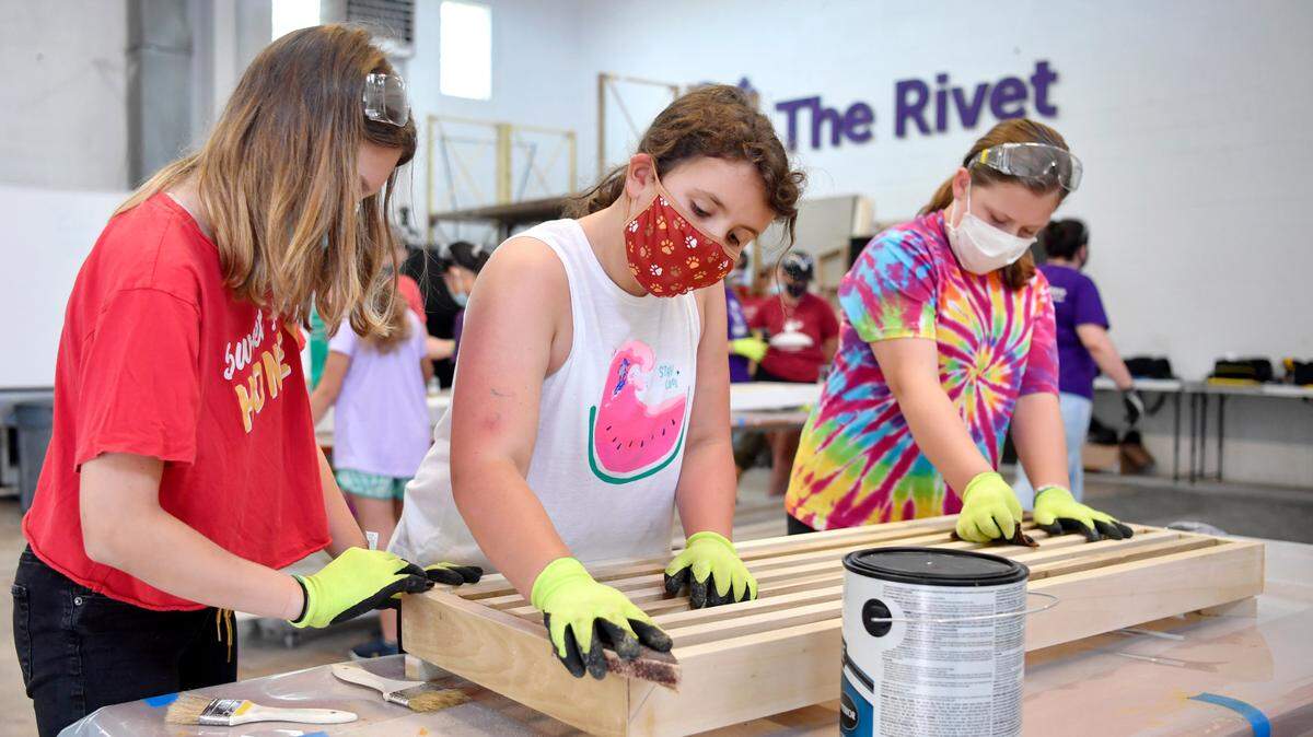 Lexi Whitehill, Kaitlyn Gutierrez and Lydia Lenz work together to sand a bench at the “GLOW” camp at the Discovery Space on Thursday, Aug. 12, 2021.
