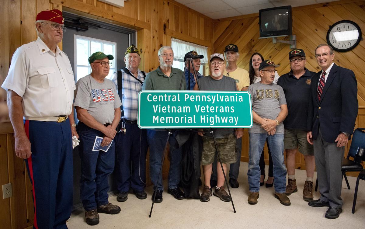 Local Vietnam veterans gather with state Rep. Stephanie Borowicz and former state Rep. Mike Hanna Sr. around a replica of the sign for the new Central Pennsylvania Vietnam Veterans Memorial Highway on Wednesday.