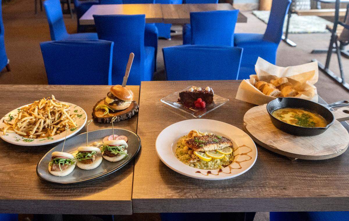 A selection of items from the Tussey Bär and Kitchen menu including house cut fries with truffle parmesan, candied pork belly confit sliders, a custom blend smash burger, Tussey’s signature Grooms Cake, a salmon feature, and flaming cheese skillet.