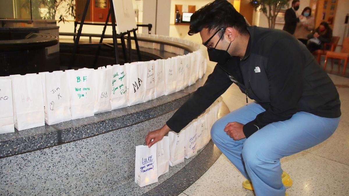 Dr. Talha Mehmood adds a luminaria Tuesday, Nov. 23, 2021, for a special patient to the display honoring those who died from COVID-19. The luminaries were placed in the Conemaugh Memorial Medical Center Atrium in Johnstown for a memorial service.