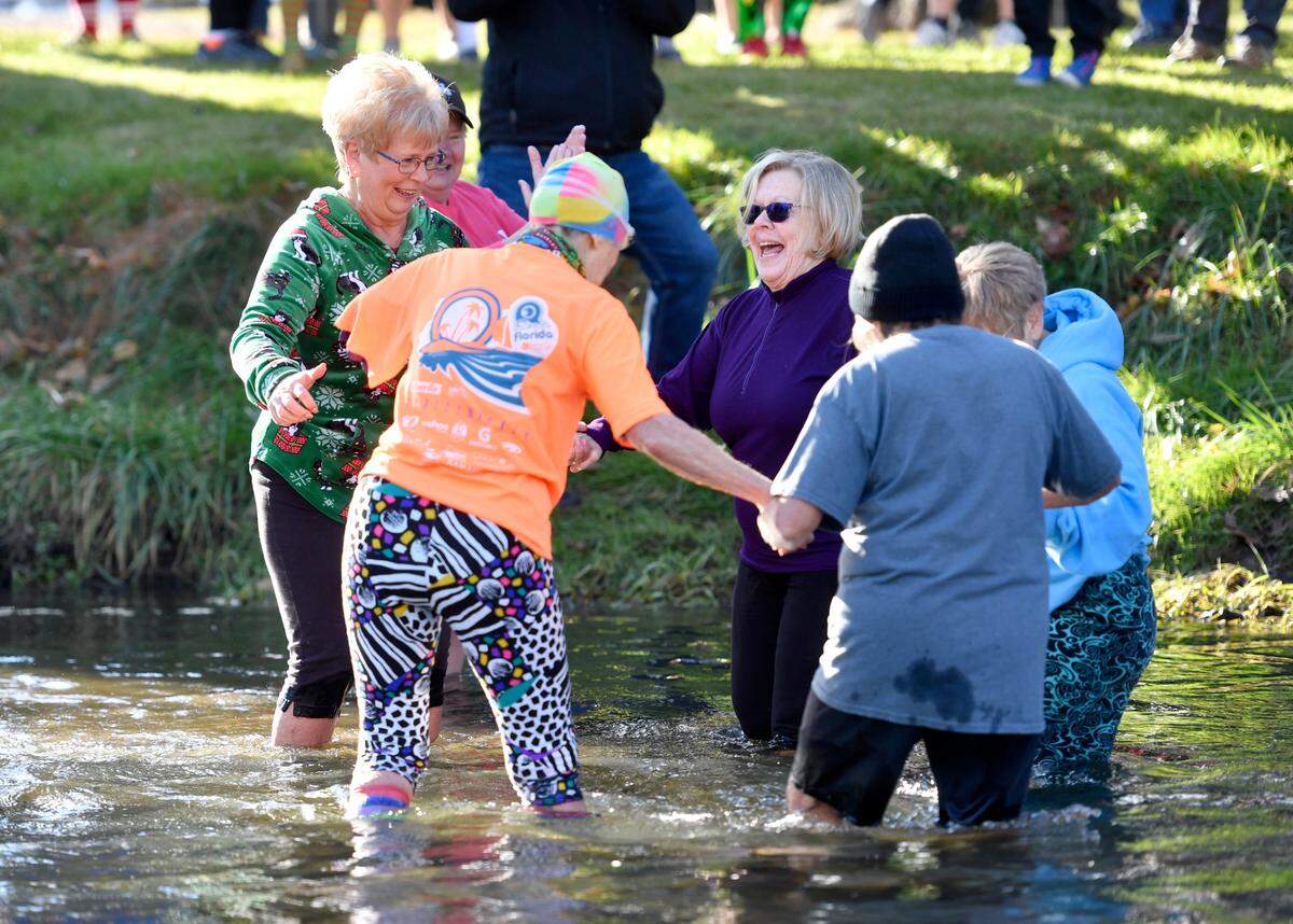Friends from a senior strength class hold hands Saturday as they wade into Penns Creek for the YMCA of Centre County Polar Bear Plunge.