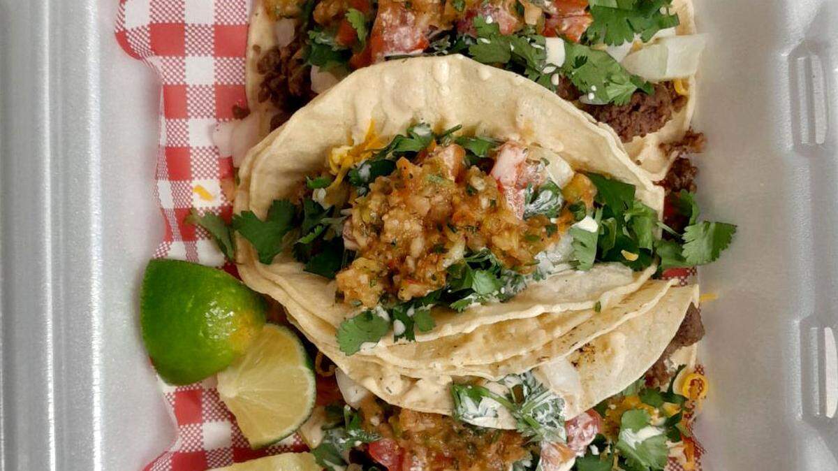 Beef tacos in corn tortillas topped with cilantro, onions, tomatoes, cheddar cheese, zesty sour cream and homemade salsa from Hilda’s Just Good Food.