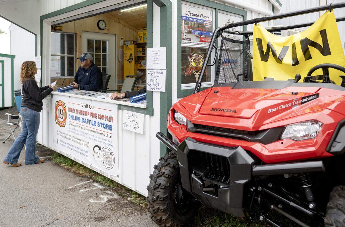 Fairgoers buy raffle tickets from the Miles Township Fire Company stand at the Centre County Grange Fair on Thursday, Aug. 21, 2025. A Honda Pioneer is the grand prize for their fun raffle in September. 
