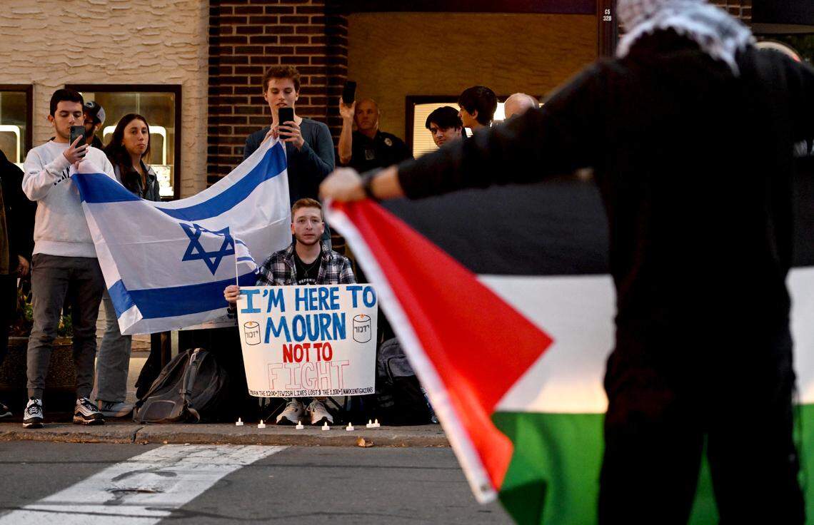 A group holding an Israeli flag sit across the street from the gathering of support for Palestine at the Allen Street gates on Thursday, Oct. 12, 2023.