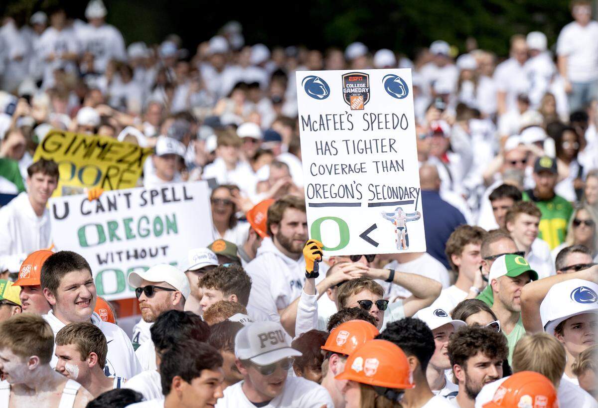 Fans hold up signs as ESPN’s College GameDay films at on Penn State’s Old Main lawn on Saturday, Sept. 27, 2025.  