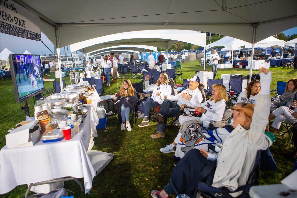 Fans enjoy watching other college football games during a tailgate by the Tailgate Guys at Penn State. Courtesy of Tailgate Guys.