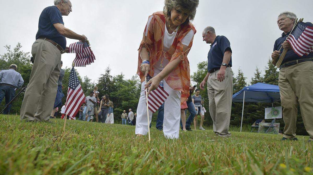 Gold Star mother Kathy Hauser-Walker of Stoystown places the first American flag into the ground at Patriot Park Global War On Terrorism Memorial Park, located near the entrance to Flight 93 National Memorial, during the official groundbreaking for phase 1 of the project on Friday.