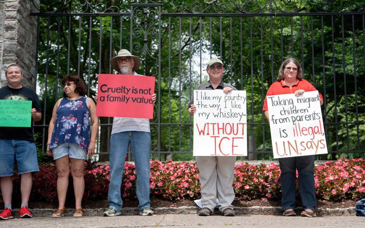 Community members hold signs and gather at the Allen Street Gates Tuesday for the #ClosetheCamps rally.