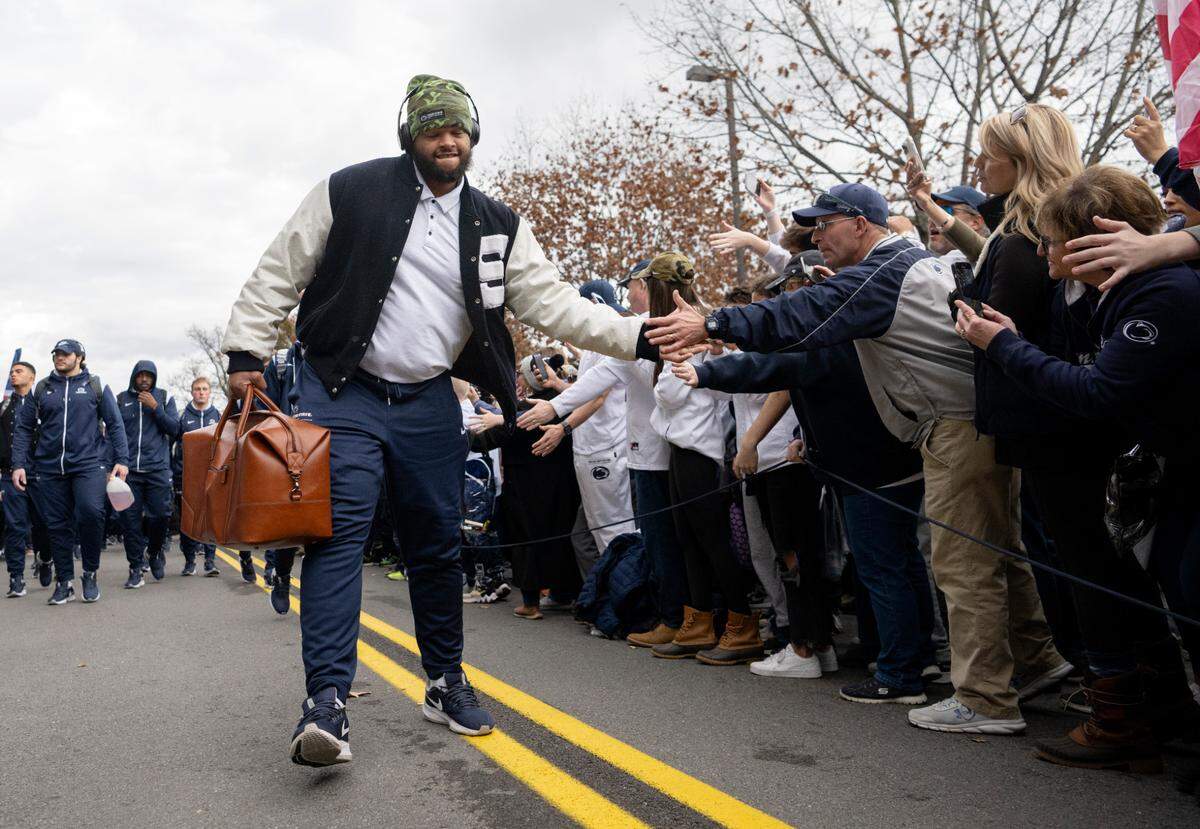 Penn State defensive tackle PJ Mustipher high-fives fans as the team arrives at Beaver Stadium for the game against Maryland on Saturday, Nov. 12, 2022.