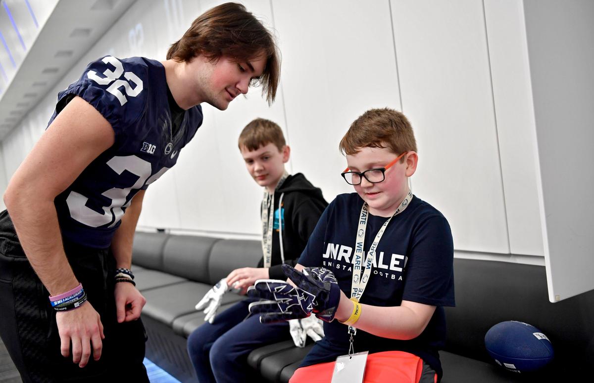 Connor Rowan, 8, tries on Penn State freshman safety Dylan Farronato’s gloves from his locker at the Lasch Football Building on Saturday, Feb. 22, 2020.