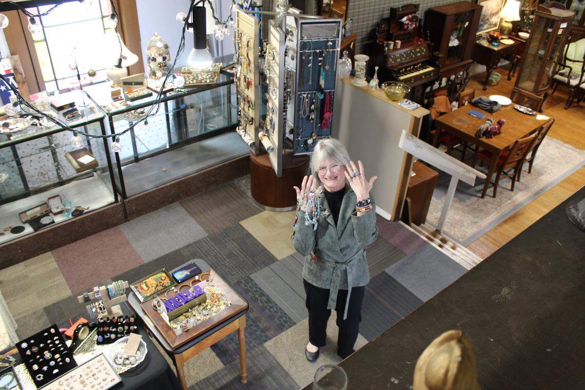 Karen Urbanski, one of the two retiring owners of The Great Mish Mosh, stands with jewelry on her hands inside her antique store on March 12, 2026.