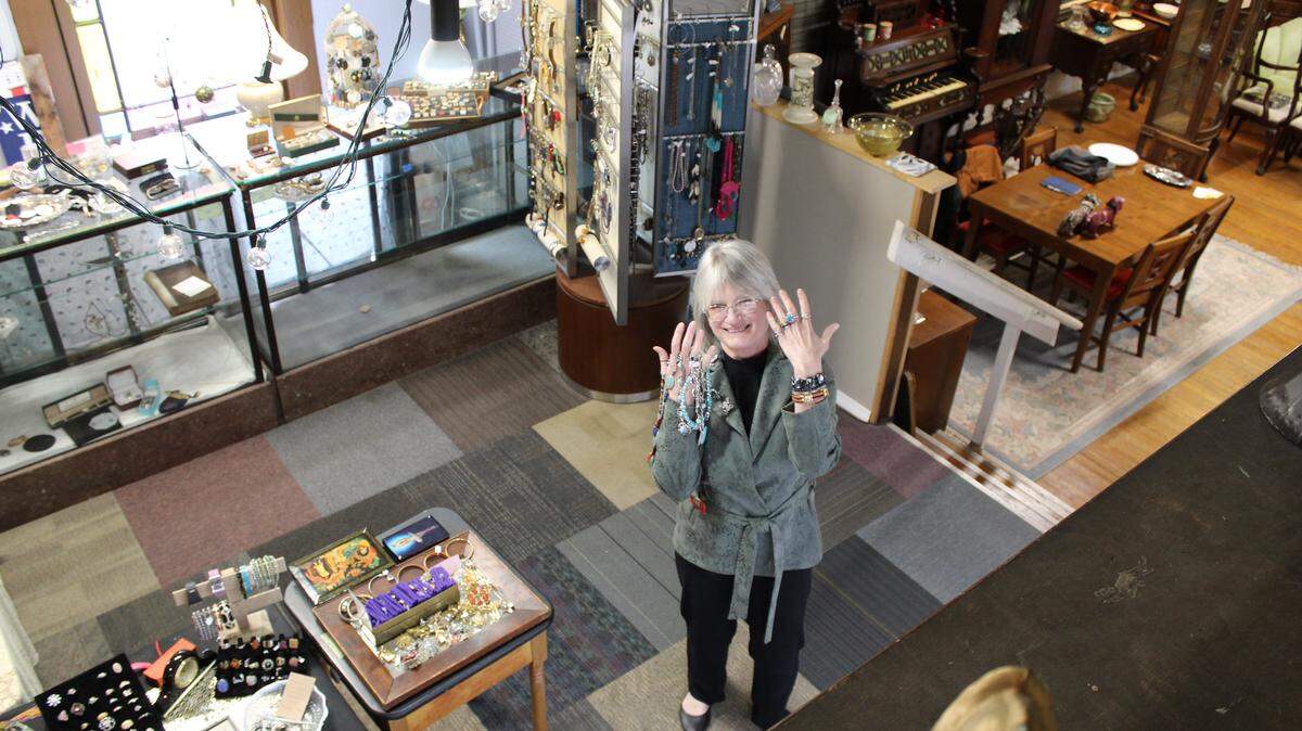 Karen Urbanski, one of the two retiring owners of The Great Mish Mosh, standing with jewelry on her hands inside her antique store.