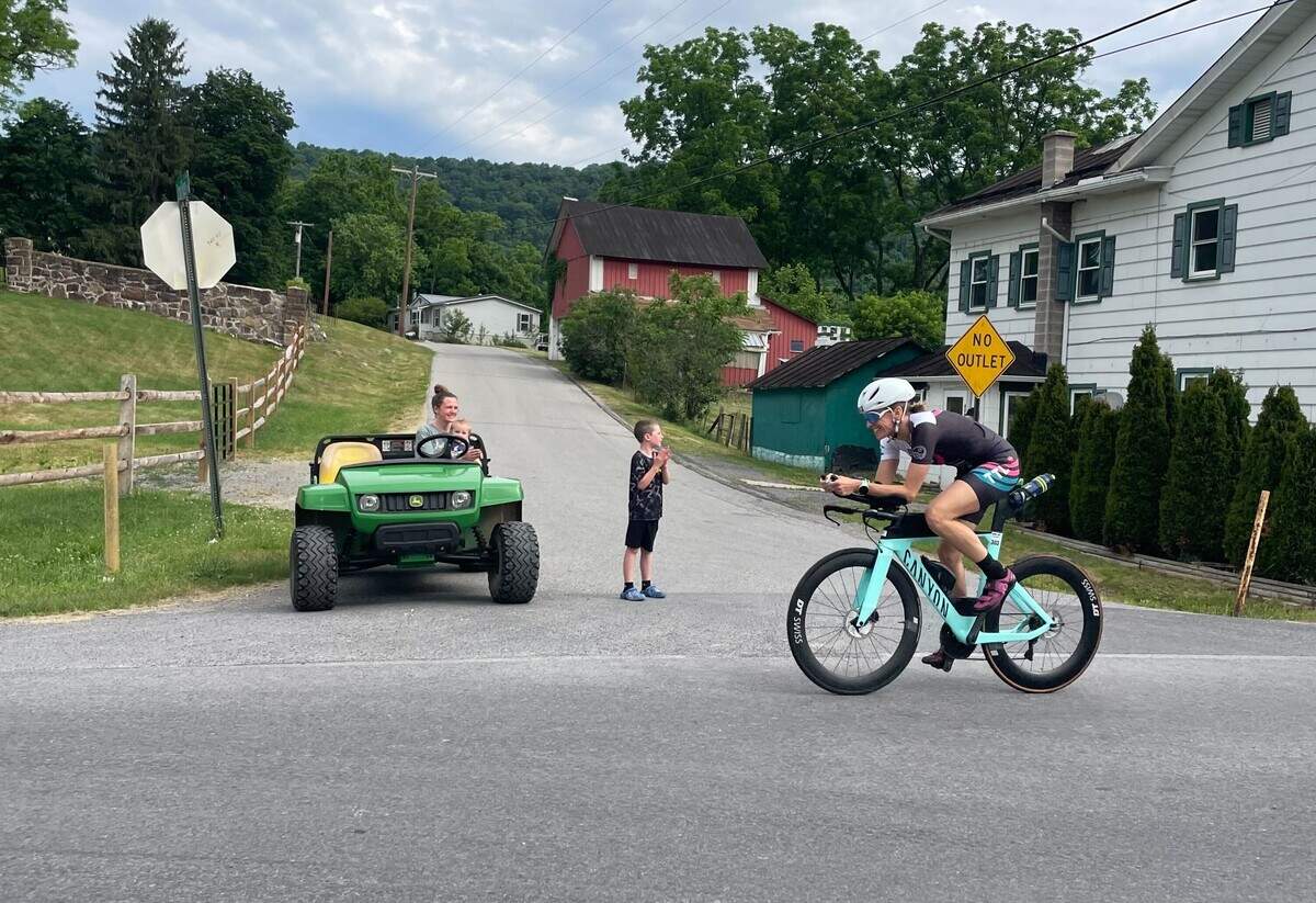 A cyclist passes by Corie Watson and her two children Sunday, June 14, 2026, at the Ironman 70.3 Pennsylvania Happy Valley North American Championship in Centre and Clinton counties.