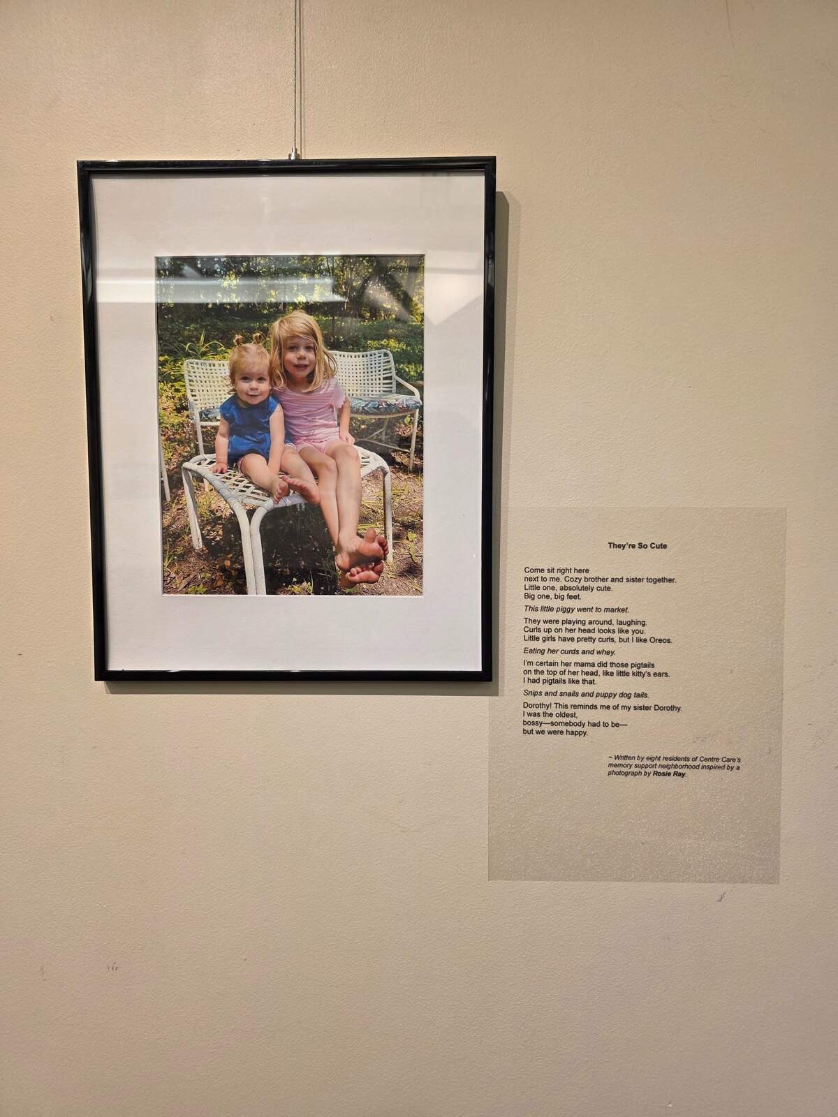 Rosie Ray’s photograph of two children hangs beside the poem it inspired.