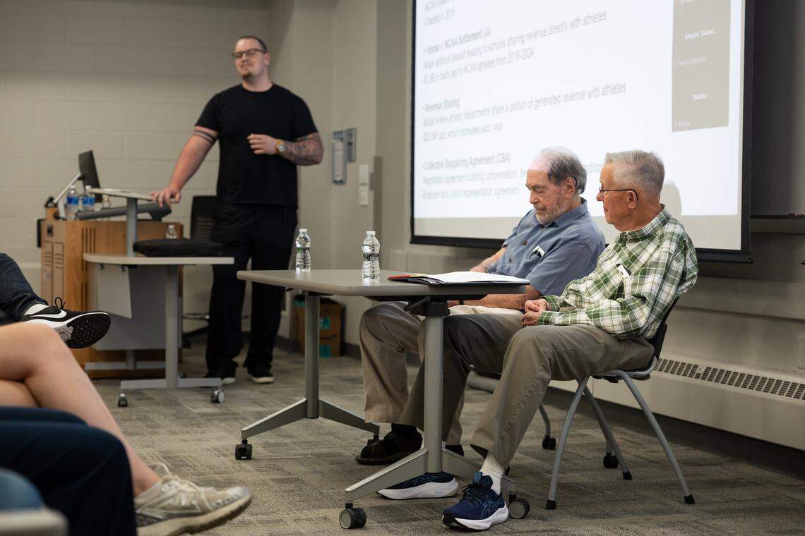 Dr. Scott R Kretchmar, left, and Dr. Ronald Smith, center, listen as Moderator Landon Tengwall, left, speaks to the crowd during a debate over whether college athletes should be paid in University Park, Pa., on Thursday, April 16, 2026. The debate was hosted by Penn State’s College of Health and Human Development.