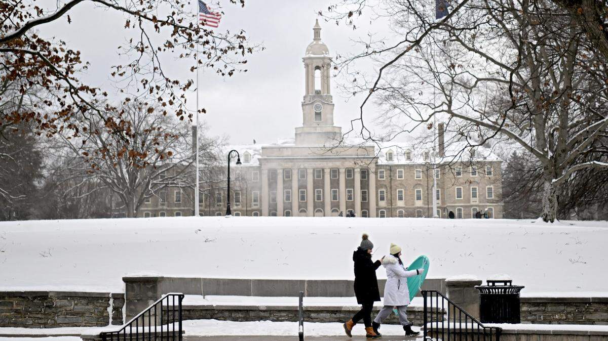 Two girls walk with a sled in front of Old Main after several inches of snow fell on Tuesday, Jan. 16, 2024.