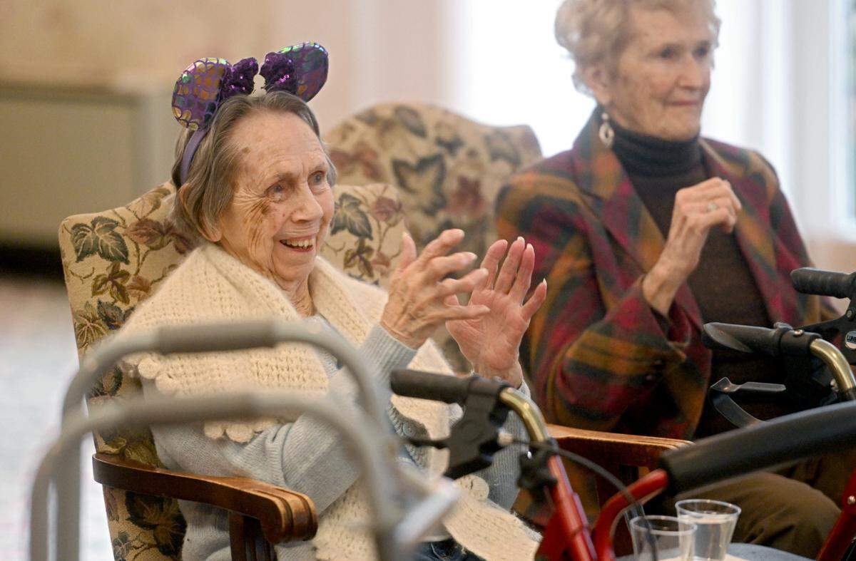 Grace Pfleegor claps along to a song during the 46-minute mini-Thon celebration Monday at Juniper Village at Brookline.
