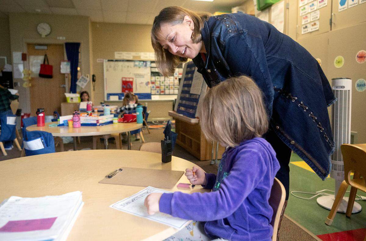 Marion Walker Elementary school principal Karen Krisch talks with a kindergarten student as they work on their letters on Wednesday, Sept. 27, 2023.