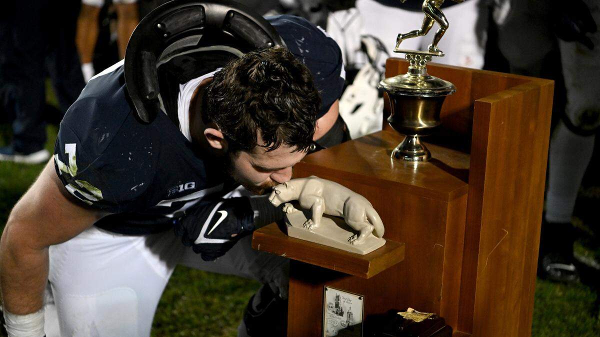 Penn State offensive lineman Bryce Effner kisses the Land-Grant Trophy after the win over Michigan State on Saturday, Nov. 26, 2022.
