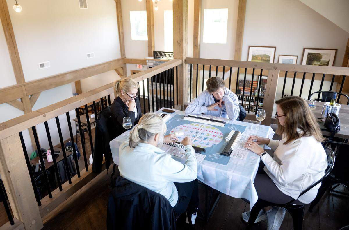 A group of friends play mahjong and enjoy a glass of wine at University Wine Company on Wednesday, May 13, 2026. 