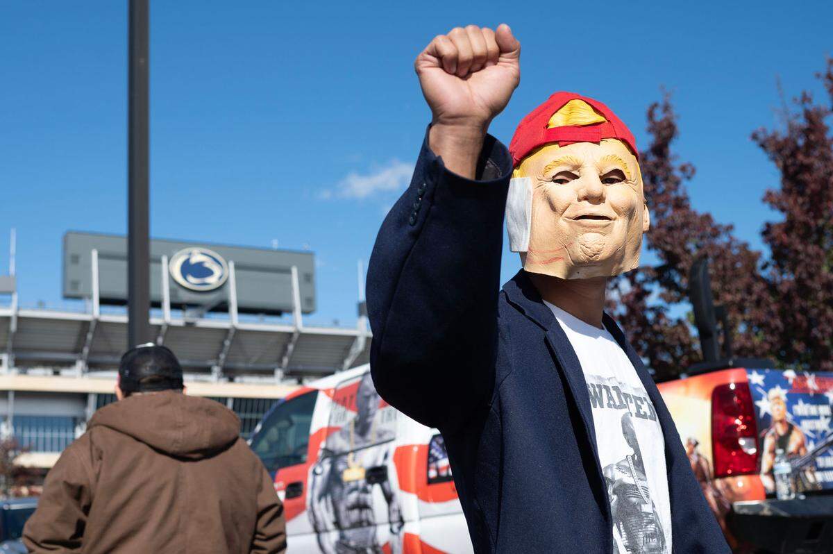 Victor Moon wears a Donald Trump mask as he holds up a fist during a Trump rally on Oct. 26, 2024.