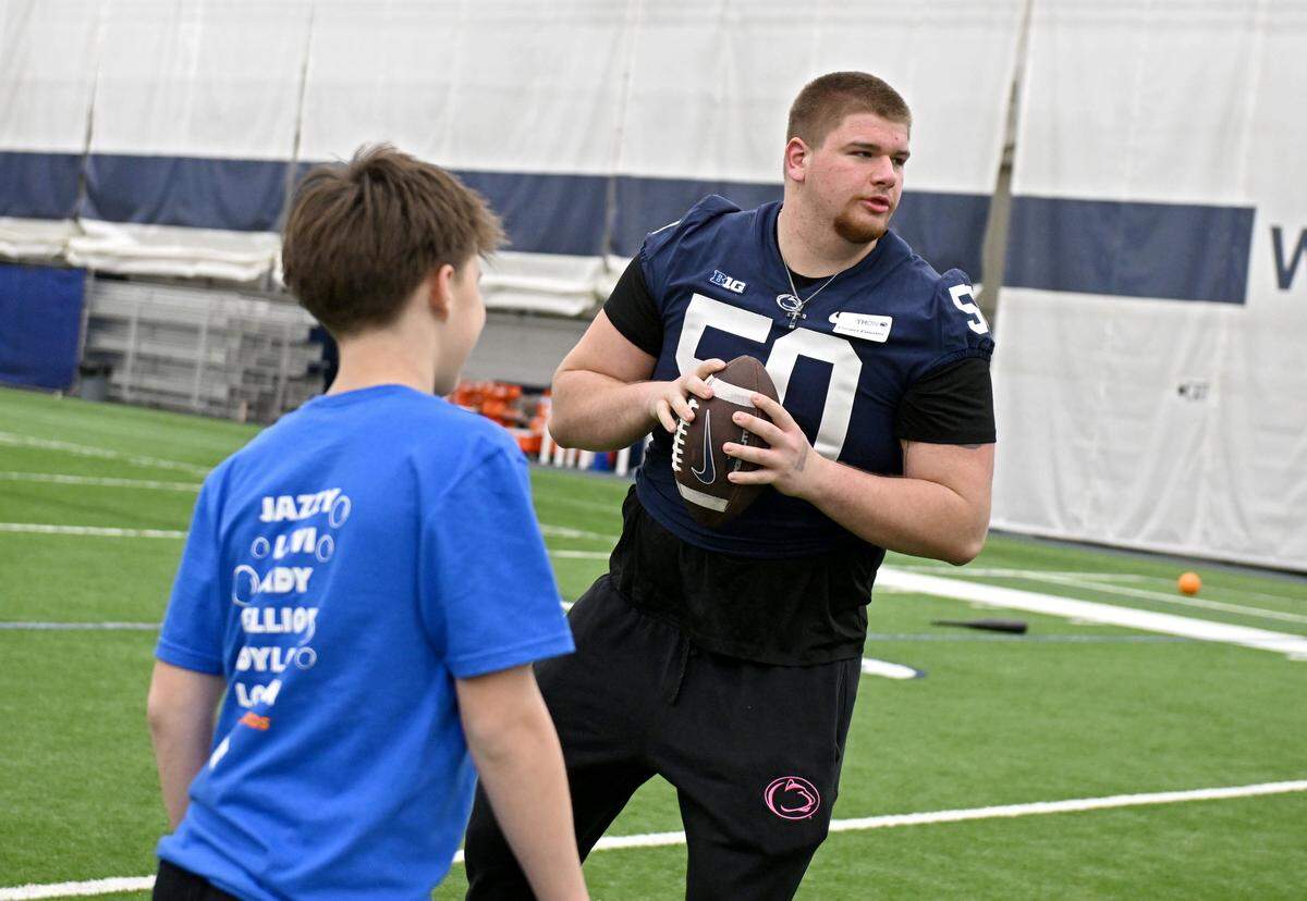 Penn State offensive lineman Cooper Cousins shows a youngster a quarterback sequence during the Thon Explorers event in Holuba Hall on Saturday, Feb. 21, 2026.  